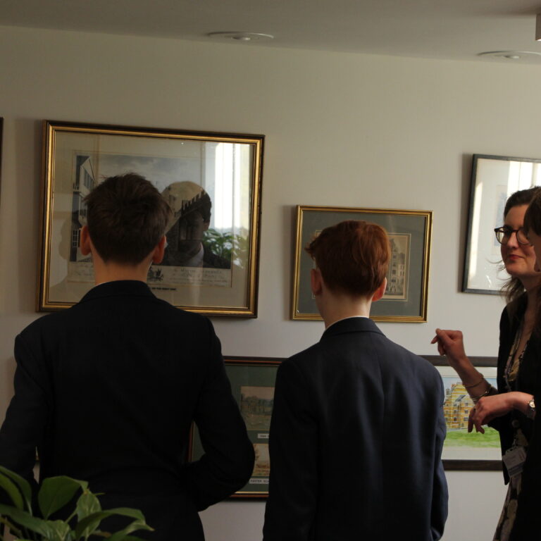 students looking at frames on a wall