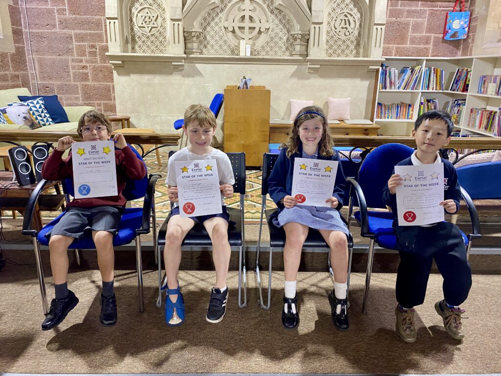 four school kids holding certificates