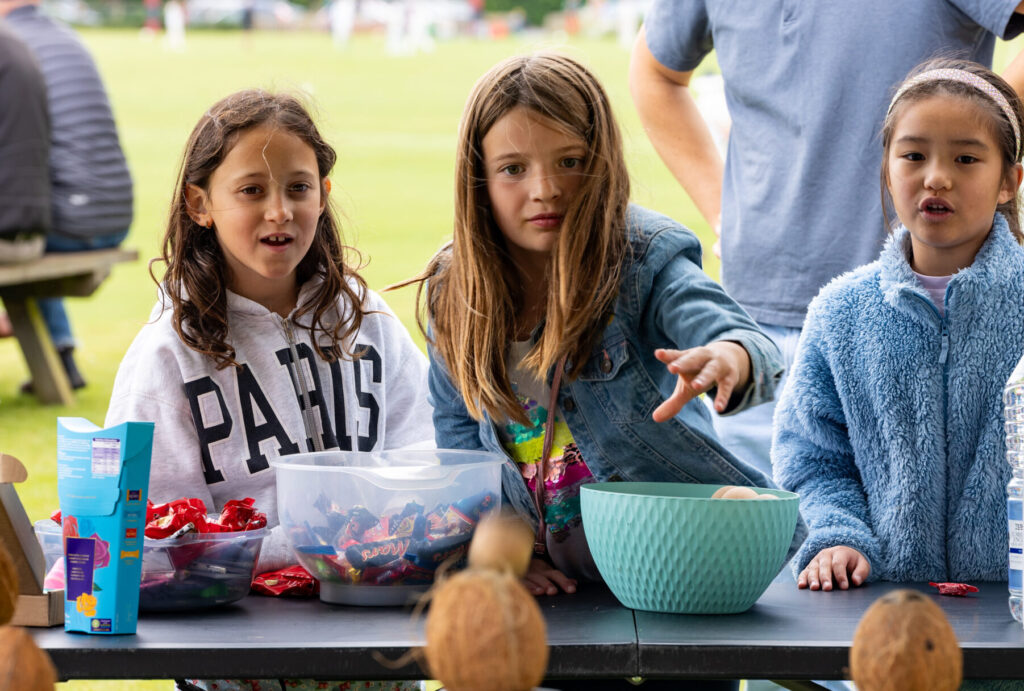 three girls standing at a table with bowls of chocolates